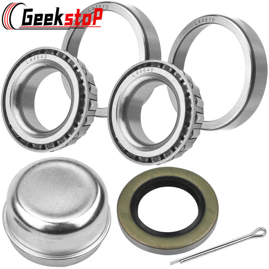 Trailer wheel bearing kit: two sets of tapered roller bearings, grease cap, rubber seal, and cotter pin. Silver bearings, black seal, and metal cap visible.